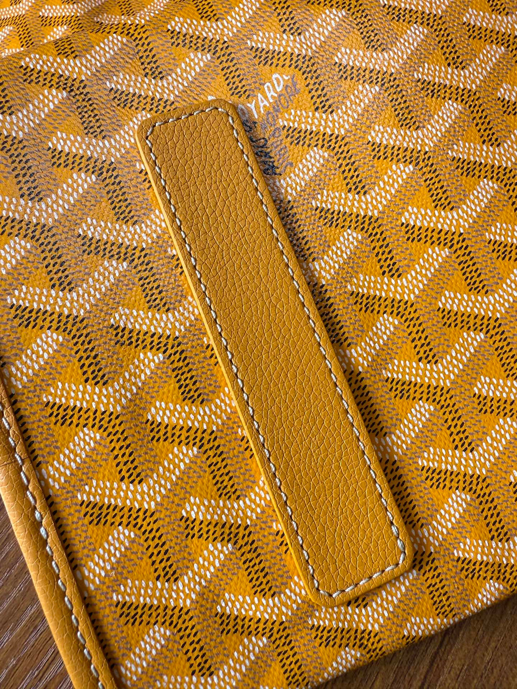 Yellow leather trim on patterned tote bag with stitched strap tab