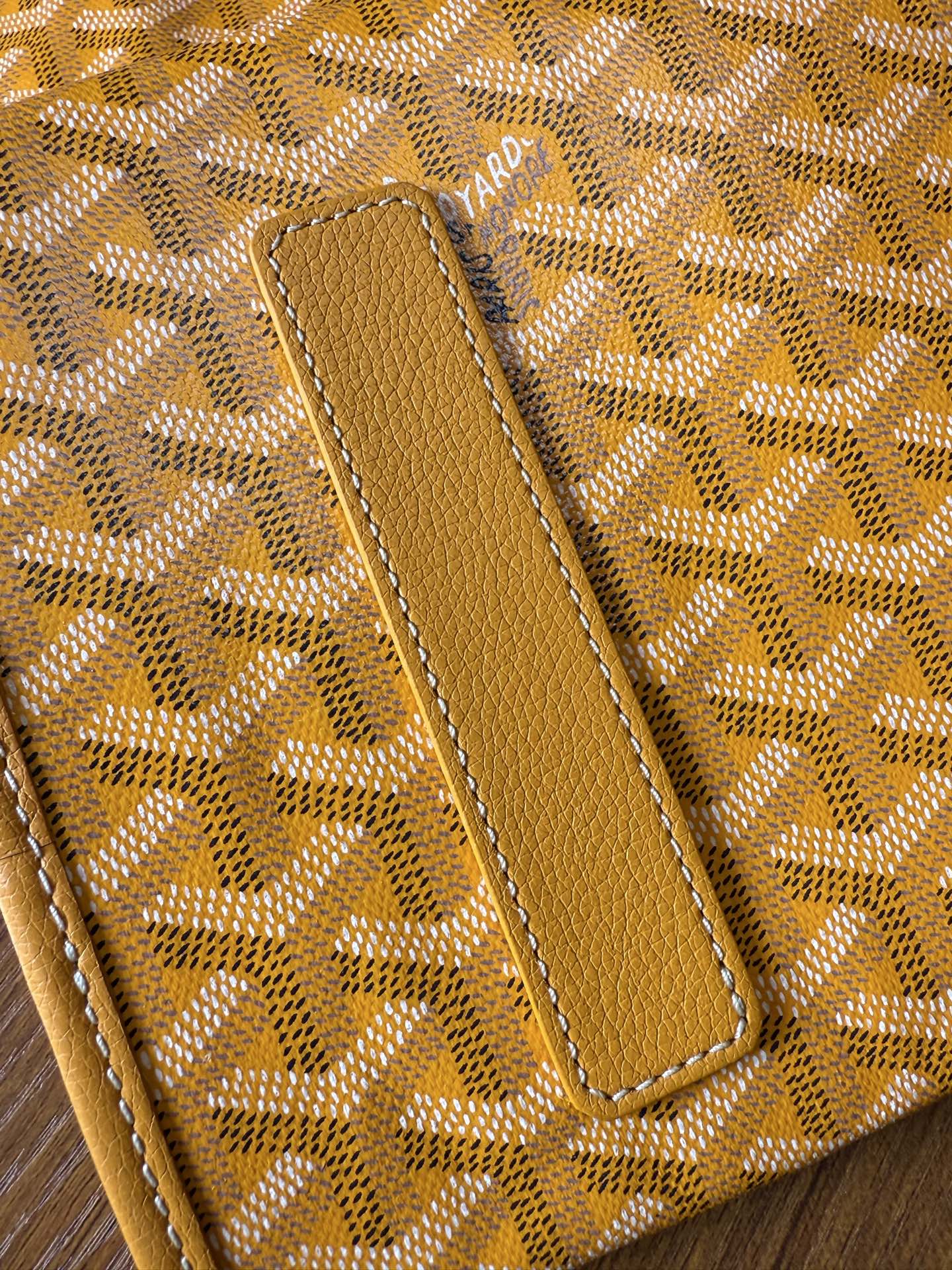 Yellow leather trim on patterned tote bag with stitched strap tab