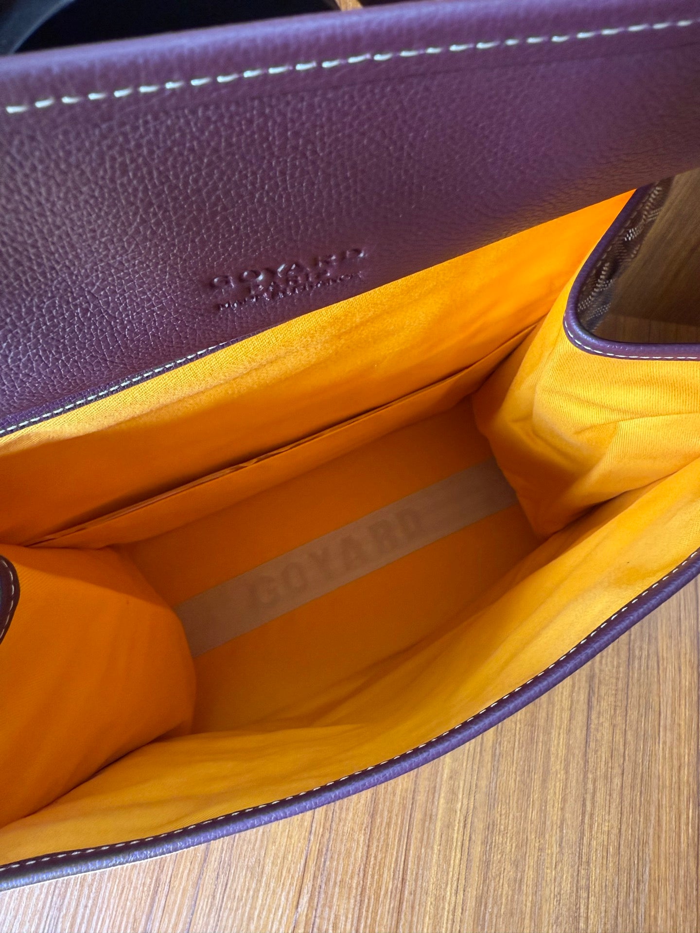 Goyard tote bag interior with bright orange lining and visible side seam stitching