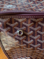 Goyard monogram tote bag side with round metal rivet and small leather brand tag