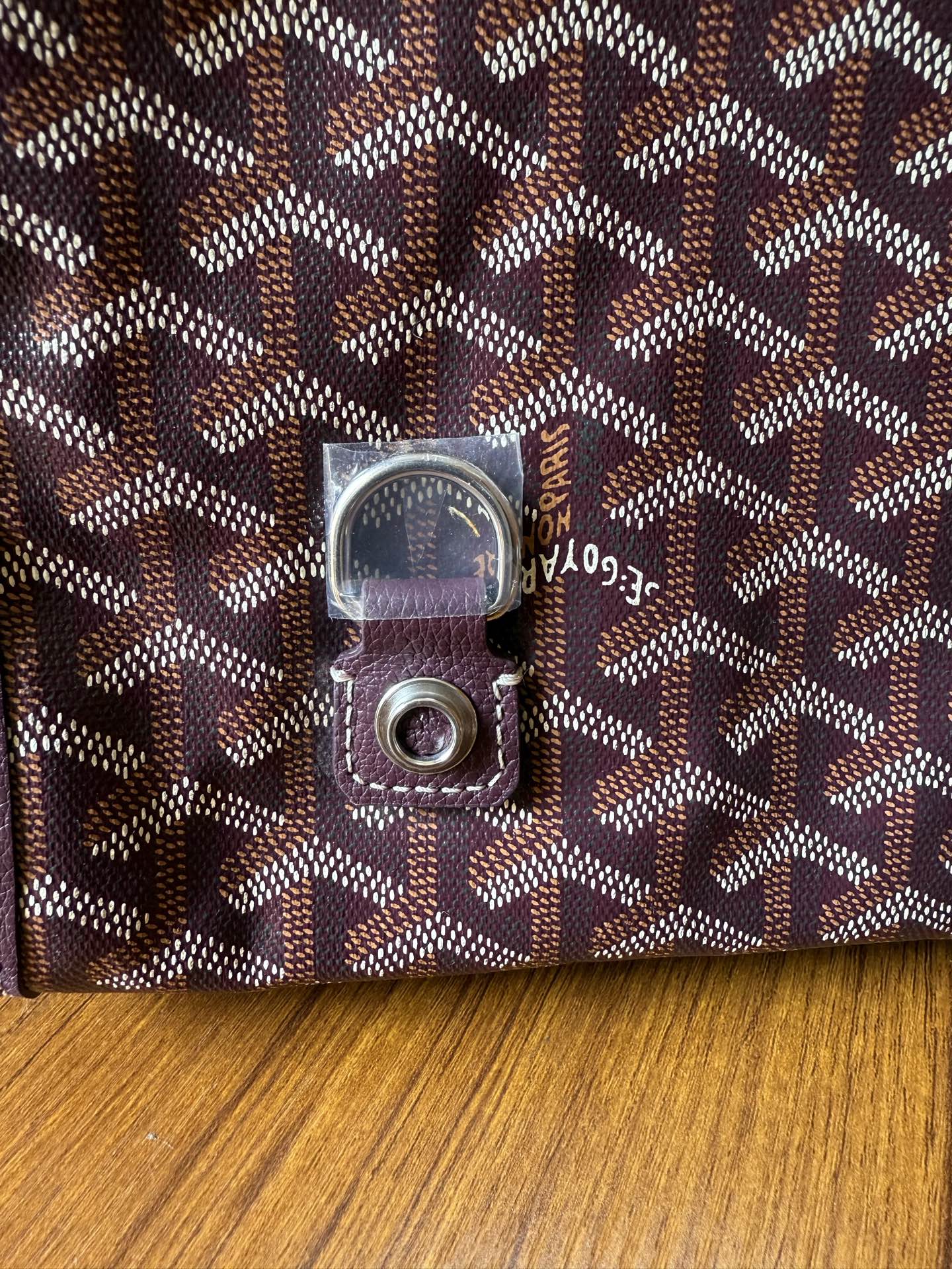 Goyard monogram fabric bag with square metal logo hardware and stitched leather edge