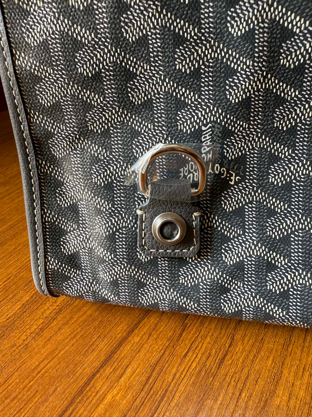 Gray patterned handbag clasp with round metal lock on the front flap