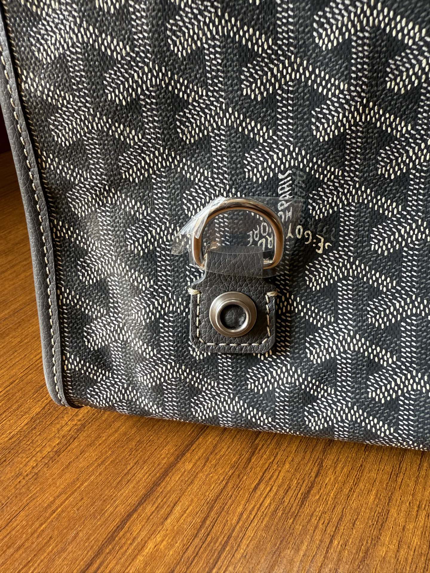 Gray patterned handbag clasp with round metal lock on the front flap
