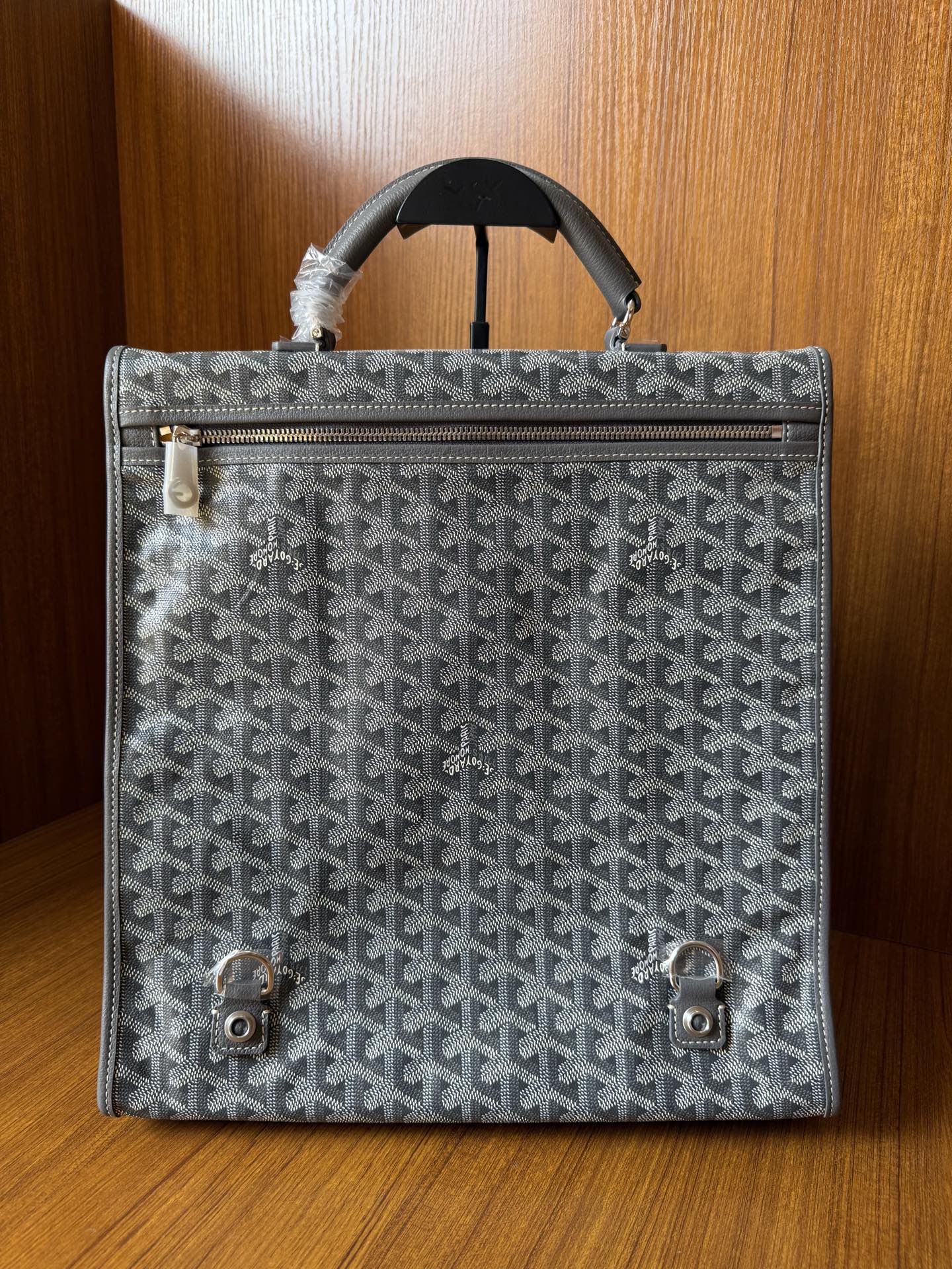 Gray patterned handbag with front zipper, flap, and metal turn-lock hardware