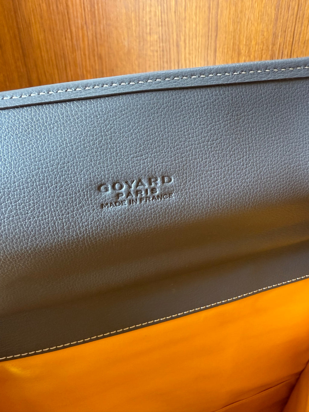 Embossed logo on light gray leather trim of a patterned handbag