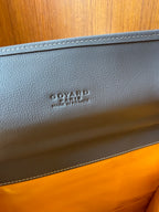 Embossed logo on light gray leather trim of a patterned handbag
