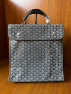 Gray patterned Goyard-style handbag with flap and black top handles