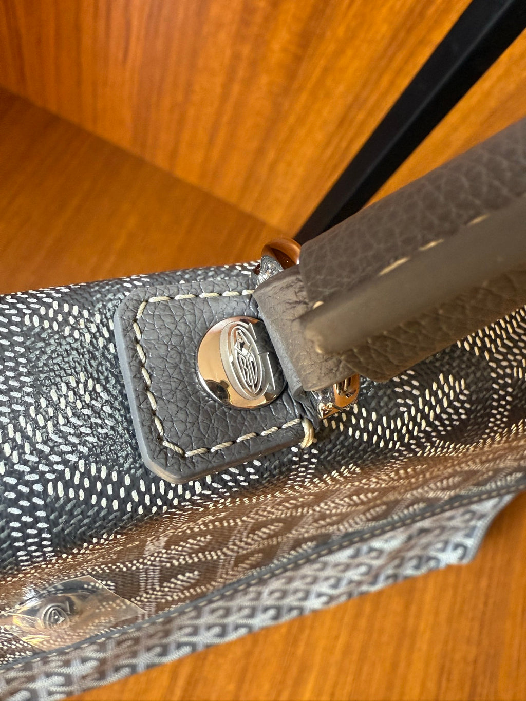 Corner latch with metal button and leather trim on gray patterned handbag