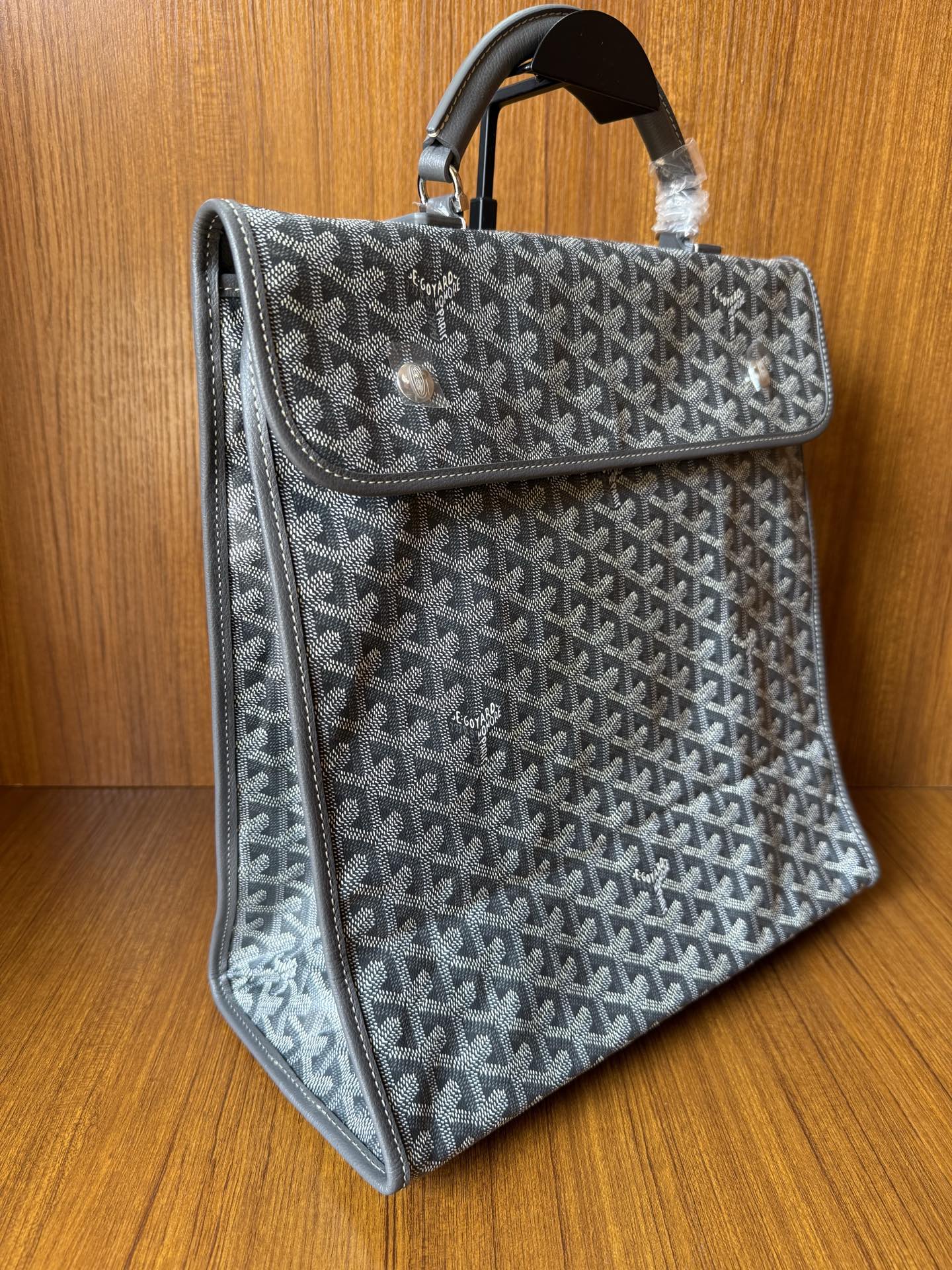 Structured gray patterned handbag with top handle and long side flap