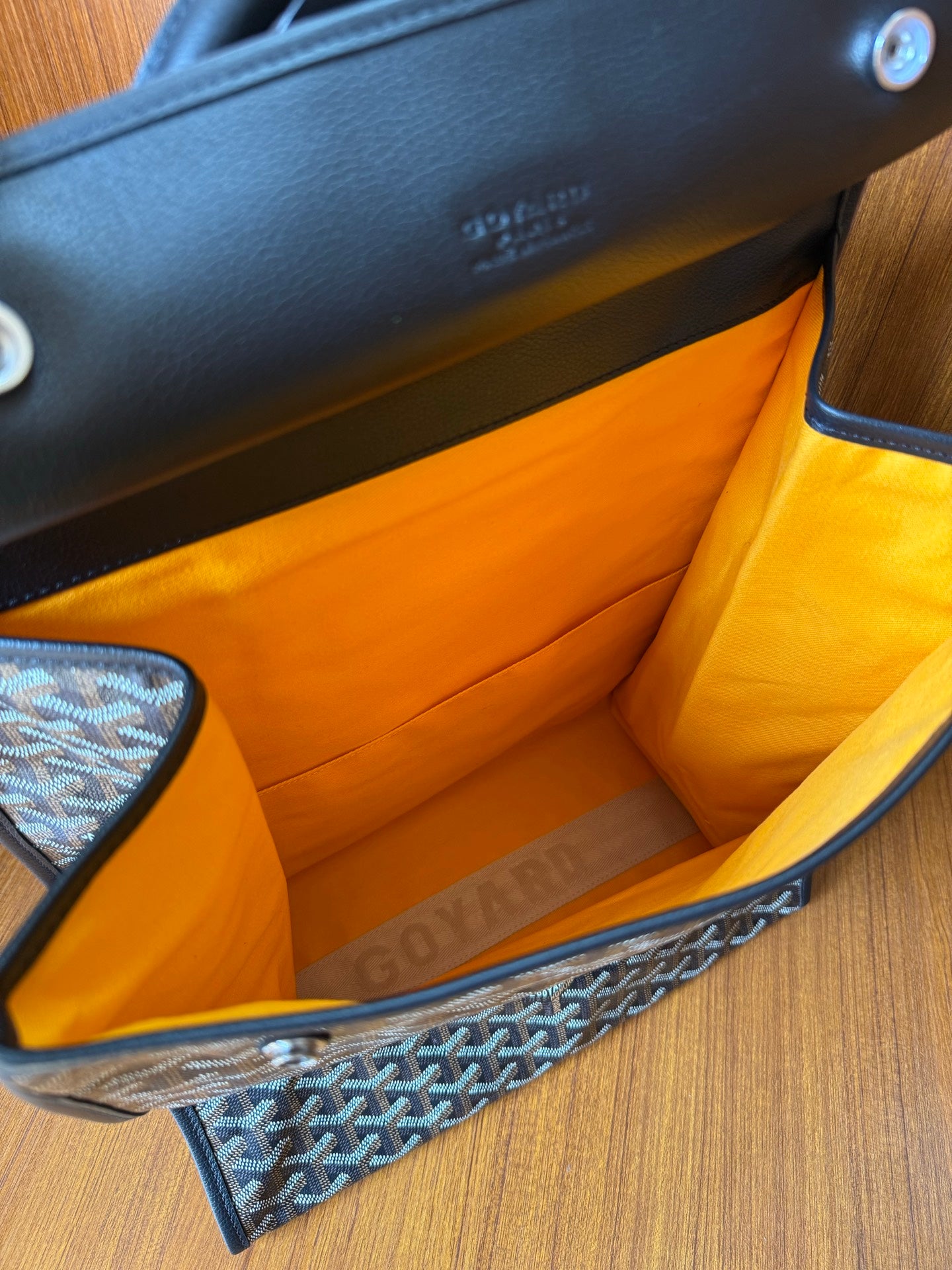 Bag interior with orange lining and dark trim, Goyardine patterned exterior.