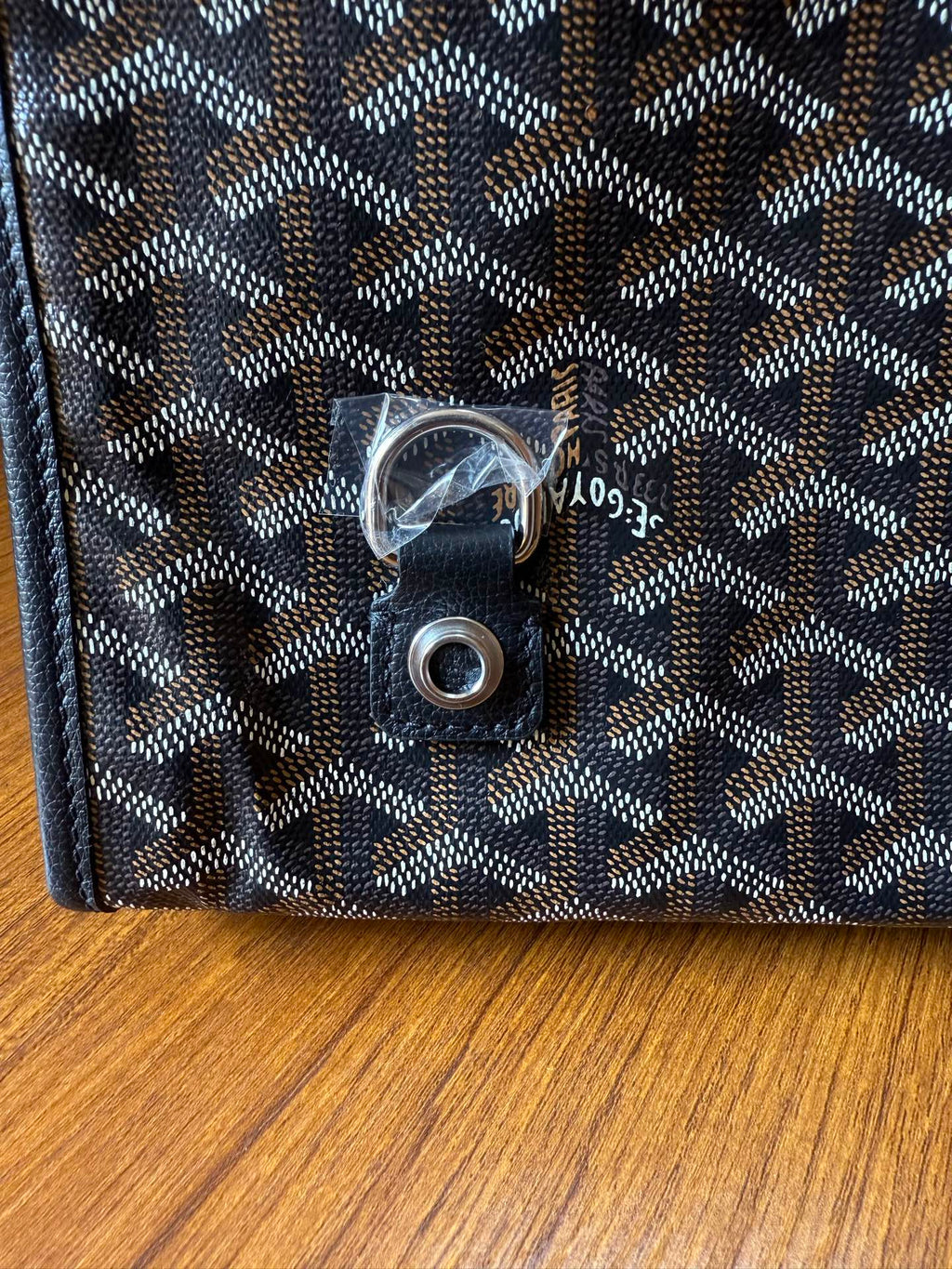 Close-up of snap button and metal hardware on Goyardine bag, dark blue-gray.