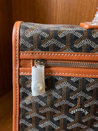 Designer tote bag close-up with Goyard-style pattern, zip pocket, tan leather edging