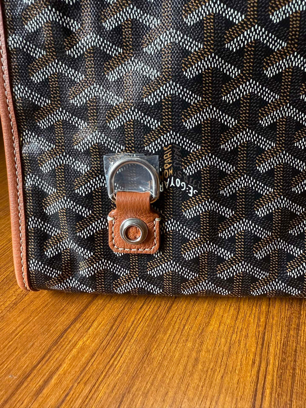Designer tote bag close-up with Goyard-style pattern and leather key fob with metal ring