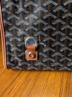 Designer tote bag close-up with Goyard-style pattern and leather key fob with metal ring