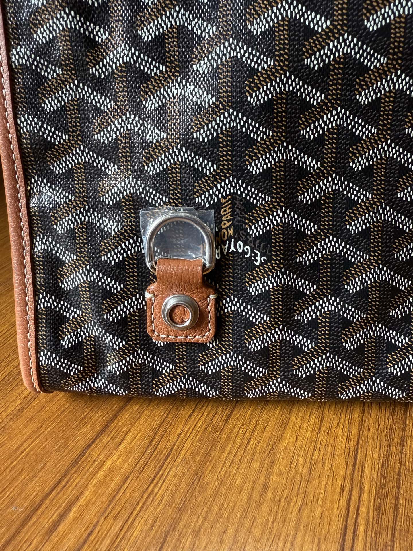 Designer tote bag close-up with Goyard-style pattern and leather key fob with metal ring