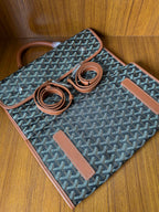 Designer tote bag laid flat with Goyard-style pattern, tan trim, two strap pieces, tag