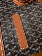 Leather trim panel on designer tote bag with Goyard-style pattern, tan stitched details