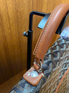 Designer tote bag top handle and side strap attachment with tan leather and metal hardware