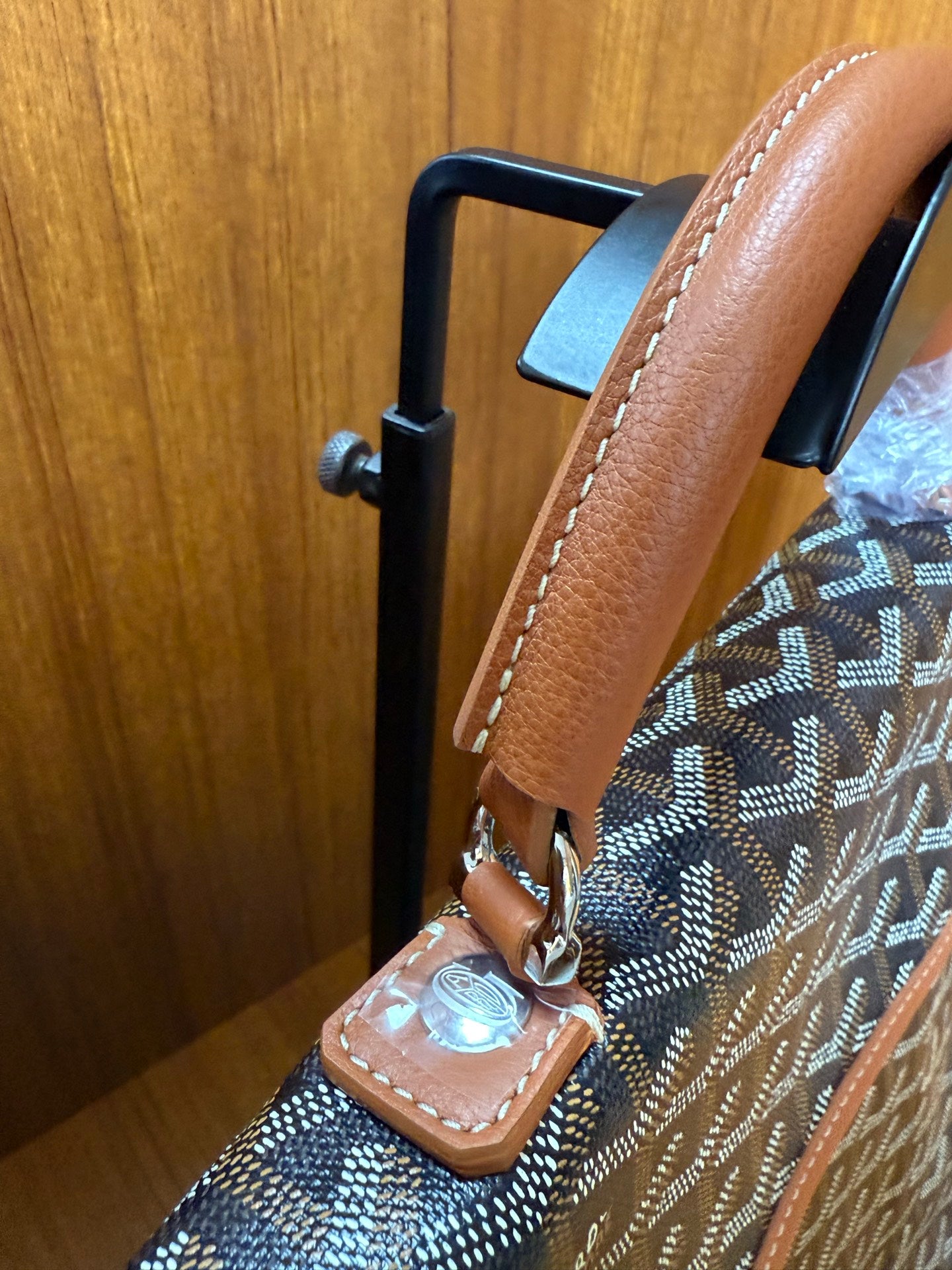 Designer tote bag top handle and side strap attachment with tan leather and metal hardware