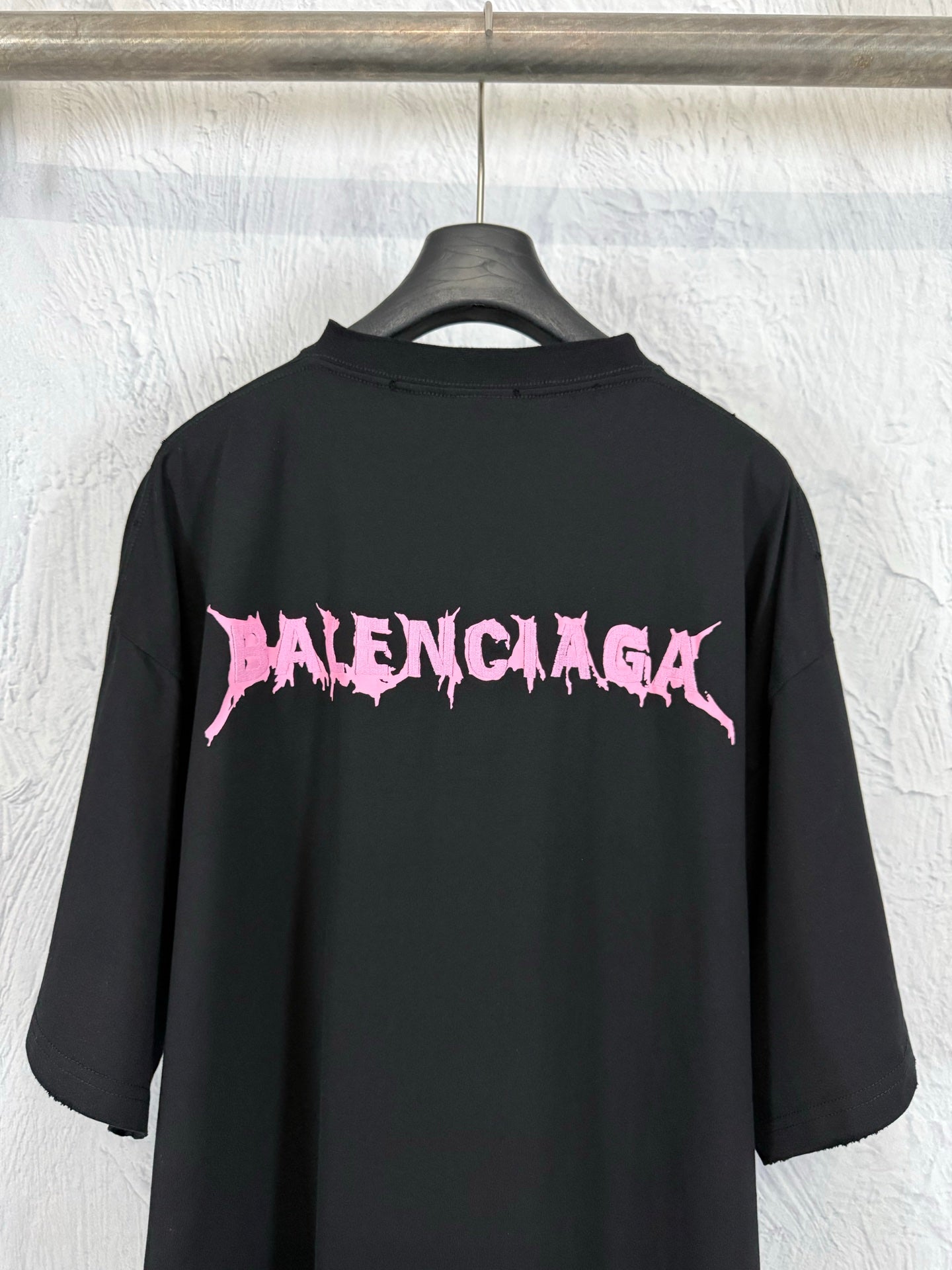 Black crew-neck short-sleeve T-shirt with large pink Balenciaga logo on the back