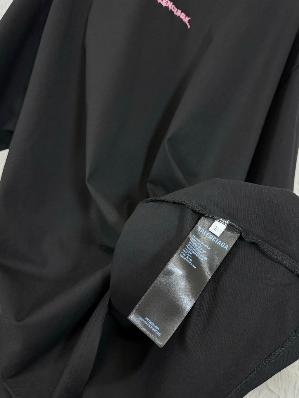 Black T-shirt fabric detail with label tag attached near the side seam