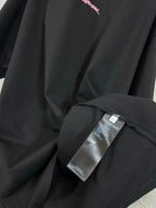 Black T-shirt fabric detail with label tag attached near the side seam