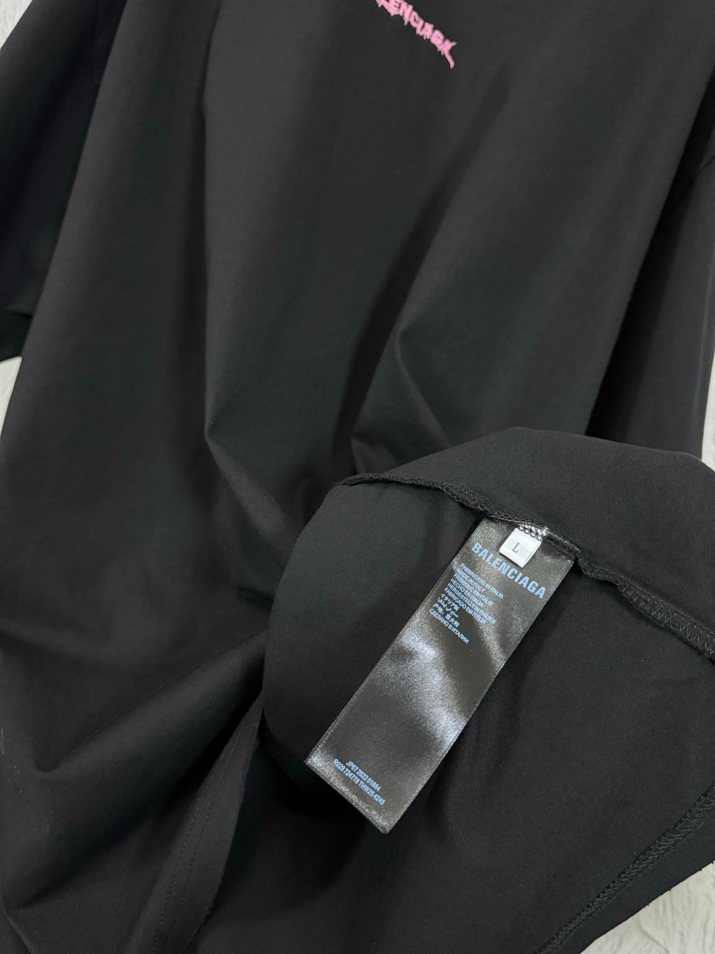 Black T-shirt fabric detail with label tag attached near the side seam