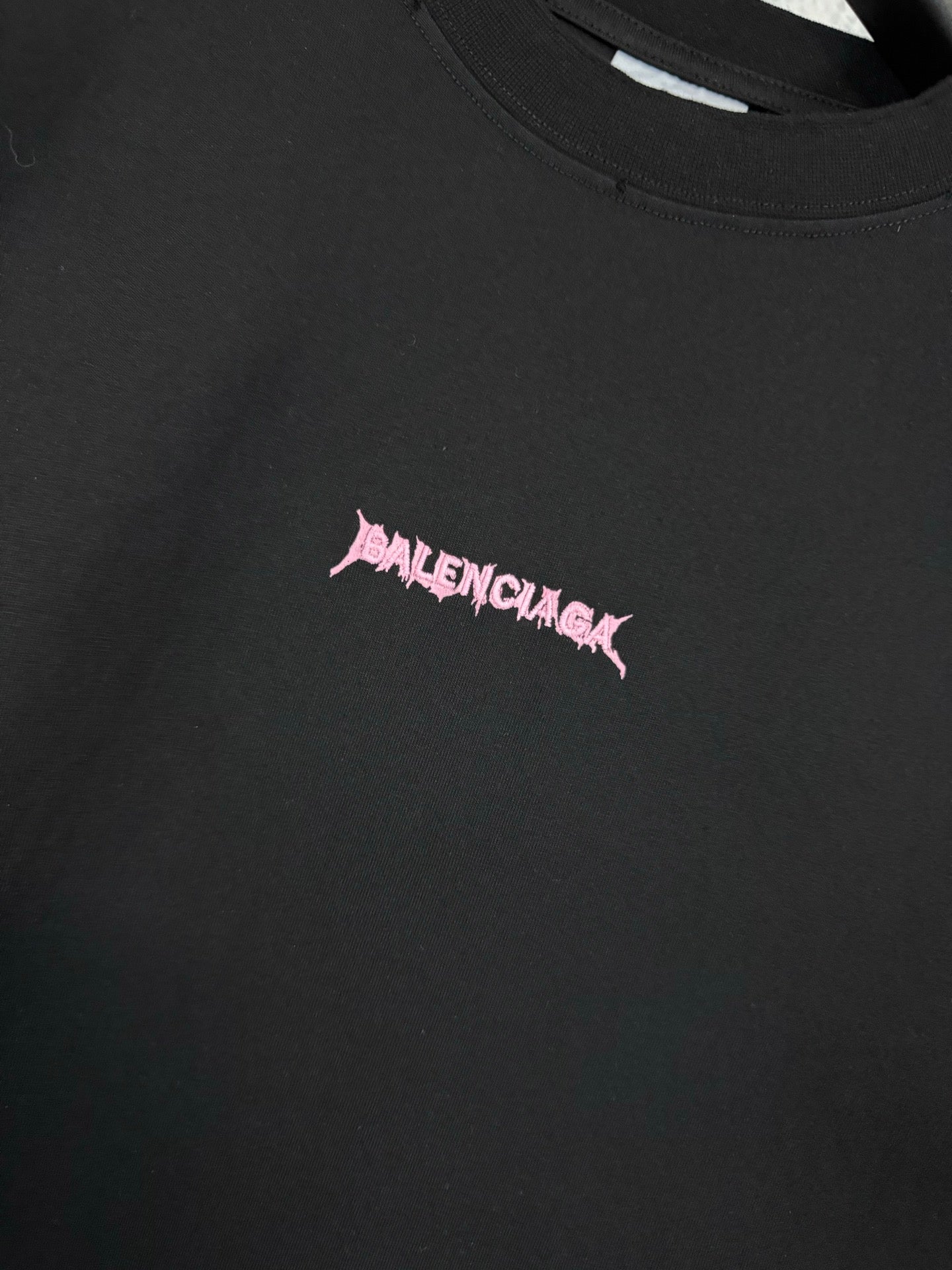 Black T-shirt chest logo detail in pink lettering