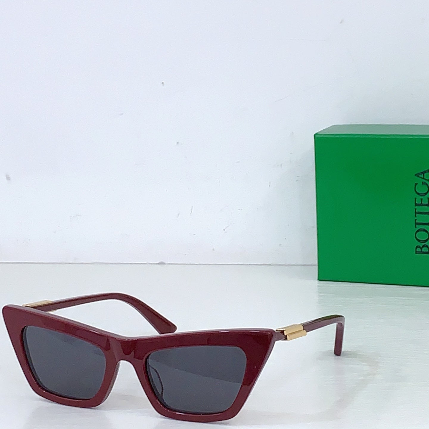 Sunglasses with burgundy cat-eye frame and dark lenses, gold-tone hinges