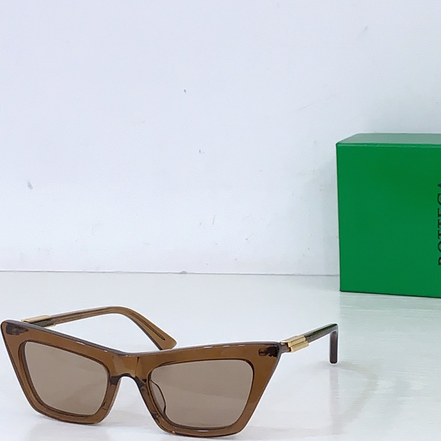 Sunglasses with brown cat-eye frame and light tan lenses, gold-tone hinges