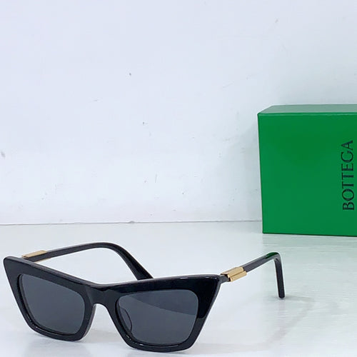 Sunglasses with black cat-eye frame, dark lenses, gold-tone hinges