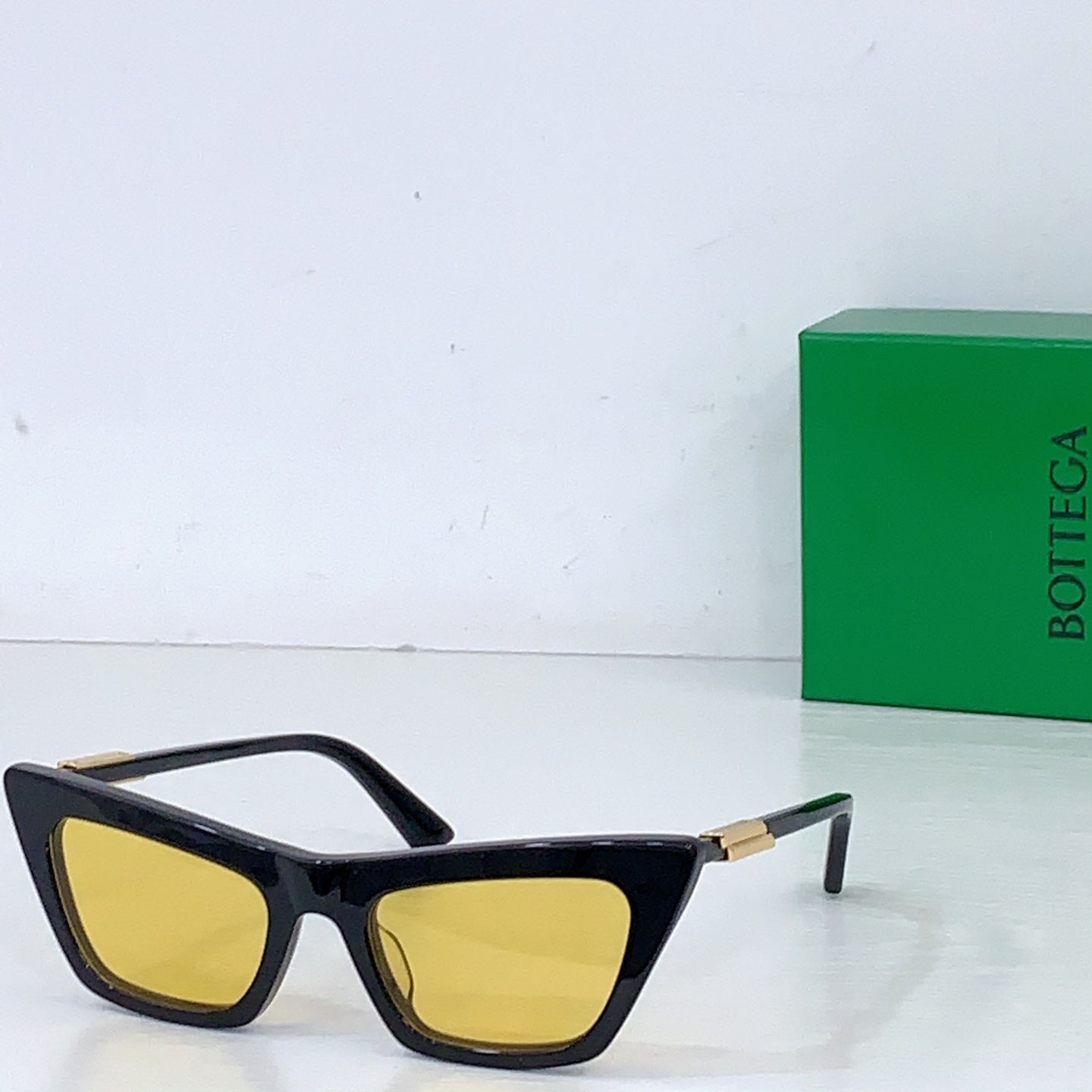 Sunglasses with black cat-eye frame and yellow lenses, gold-tone hinges