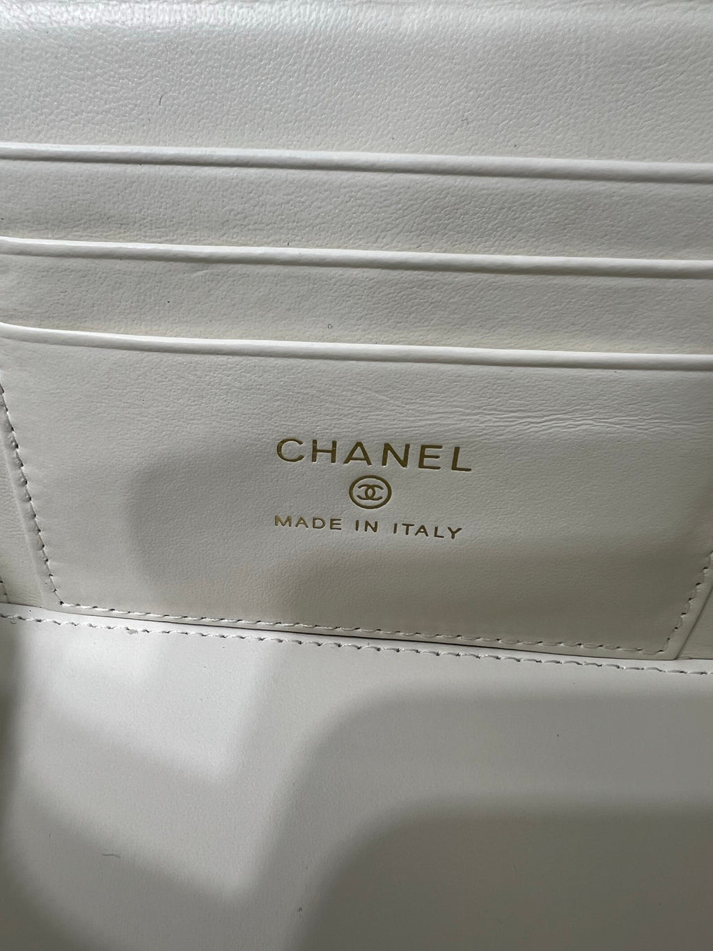 Chanel bag interior label with CHANEL and MADE IN ITALY text on white leather.