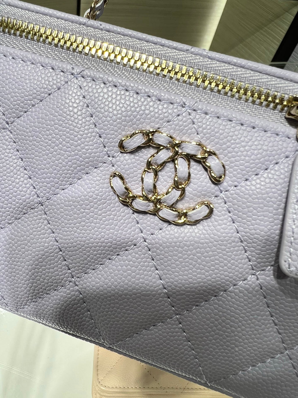Chanel mini bag close-up: quilted white leather, gold zipper and interlocking CC charm
