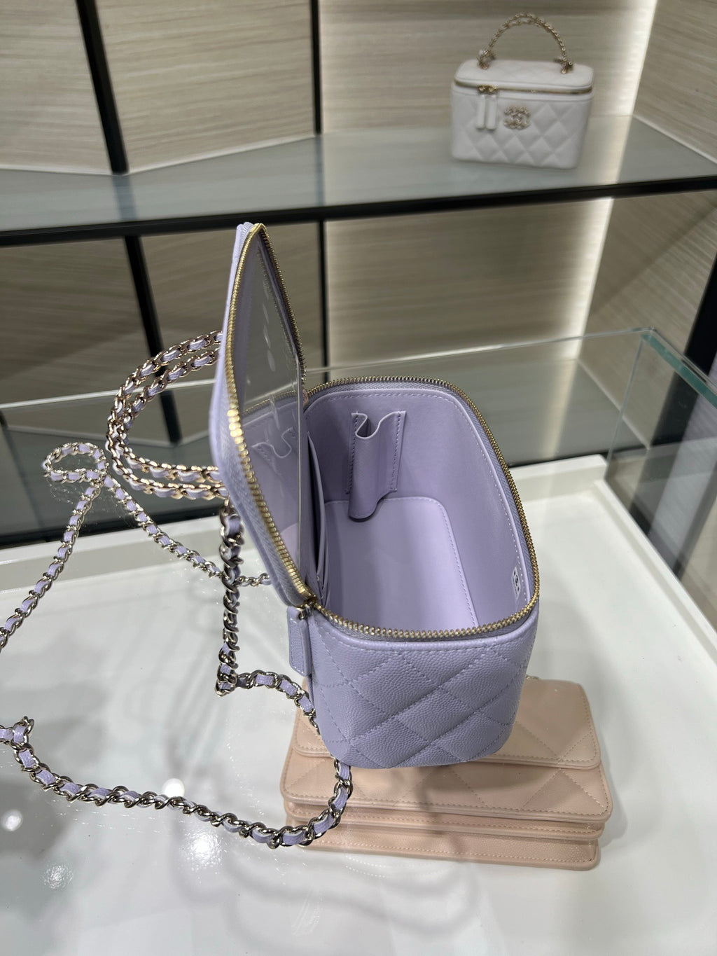 Chanel lavender mini bag open with chain strap and gold zipper, showing interior lining