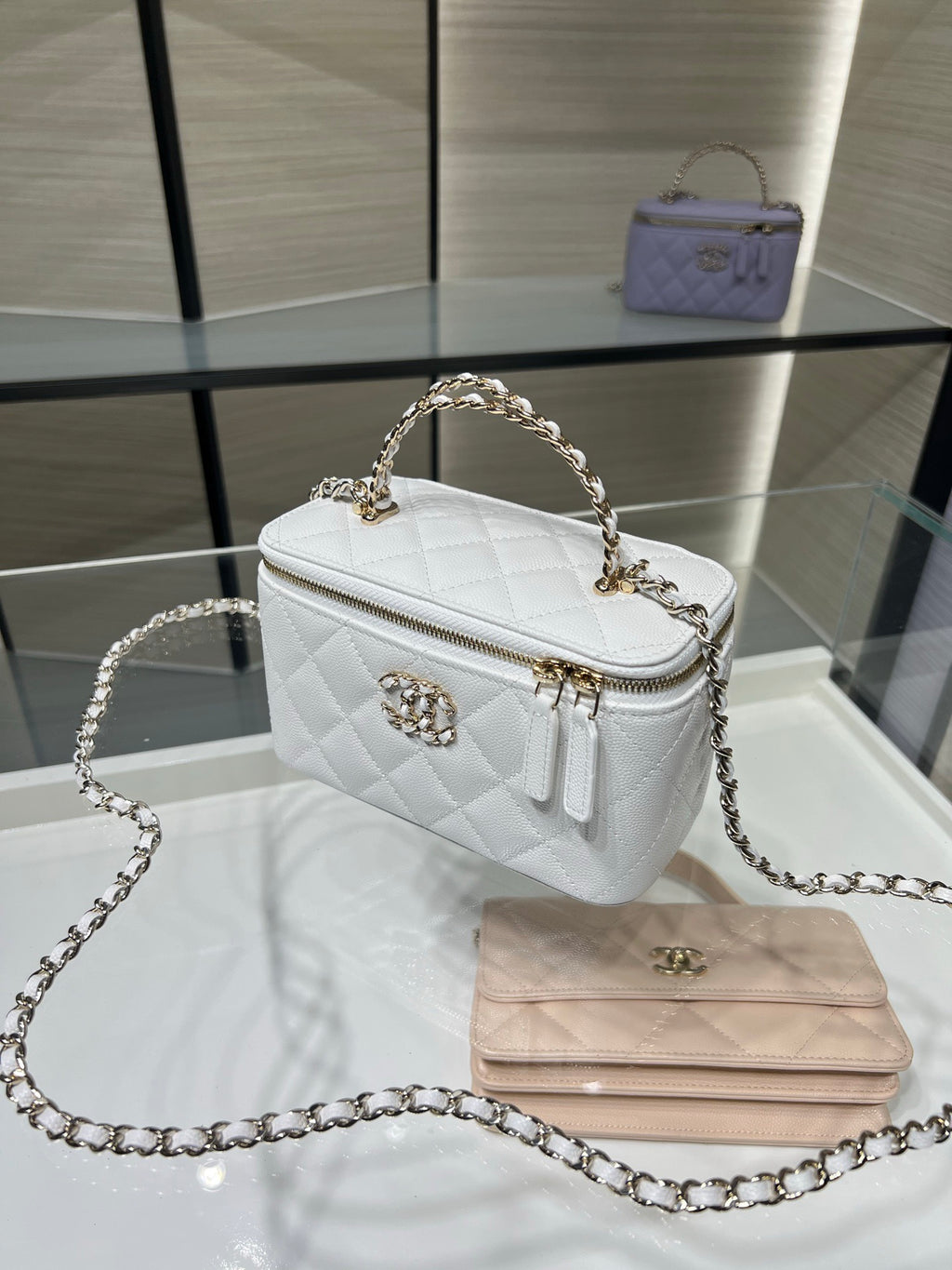 Chanel mini bag in white leather with quilted pattern, chain strap, and front logo clasp.