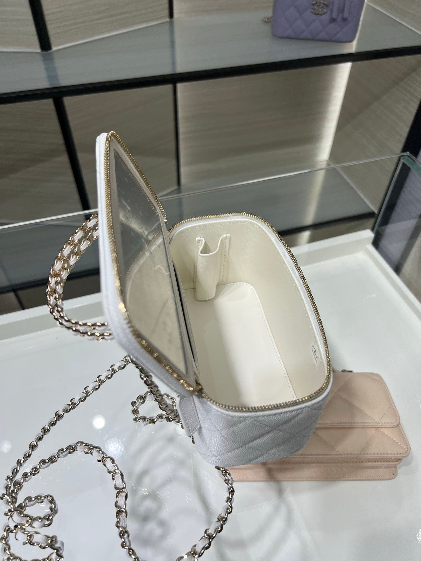 Chanel mini bag with white interior lining, open top, and quilted leather side panels.