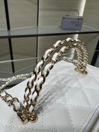 Chanel mini bag close-up with white quilted leather and gold chain strap hardware.