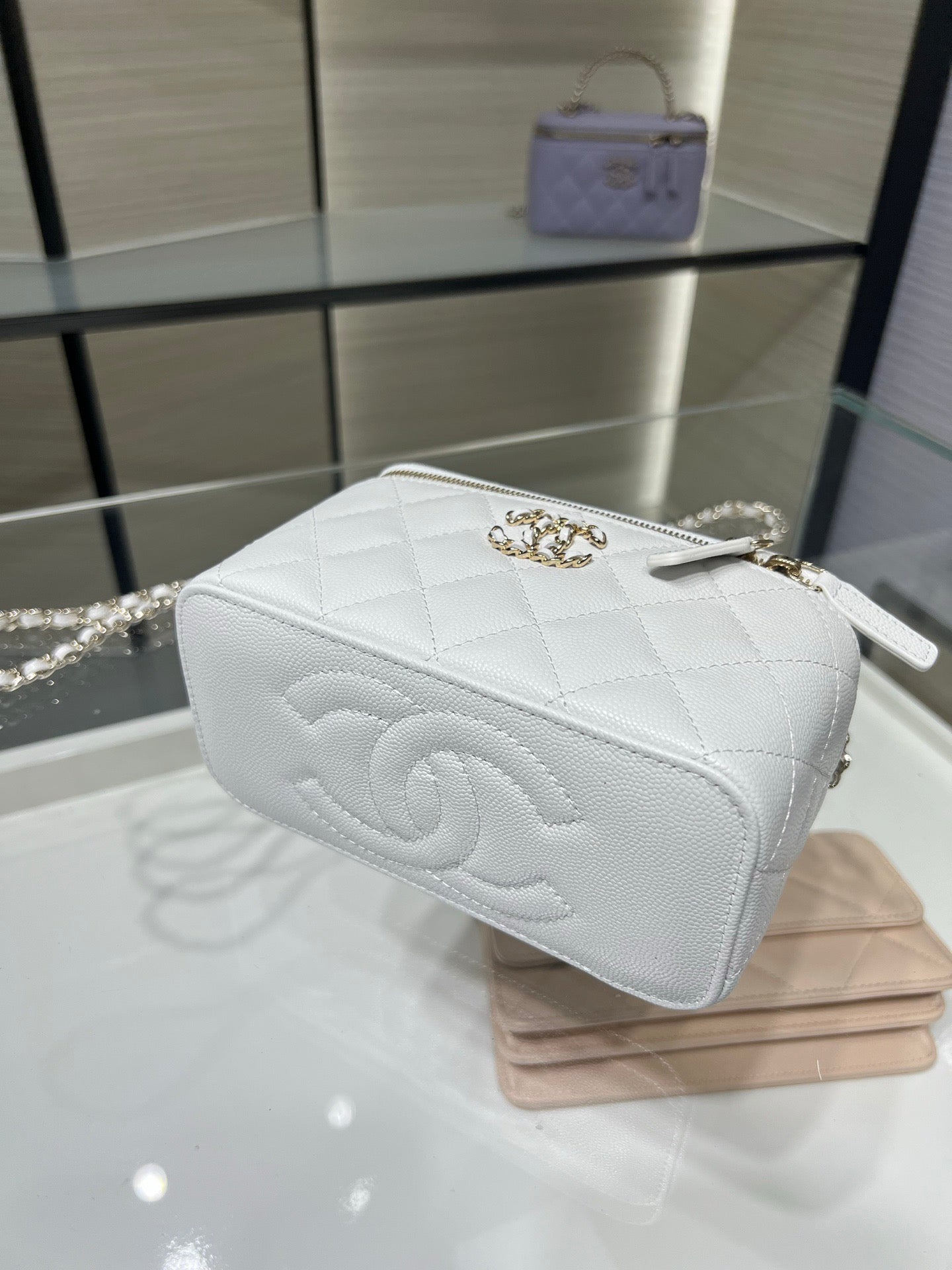 Chanel mini bag in white with quilted sides, chain handle, and top zipper closure.