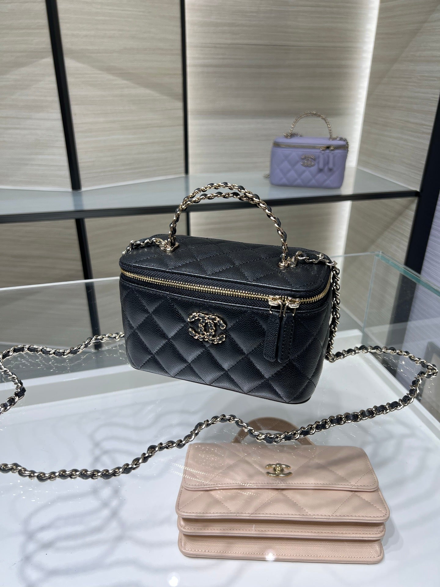 Quilted Chanel mini handbag with chain handle, top zip, and gold-tone logo emblem.