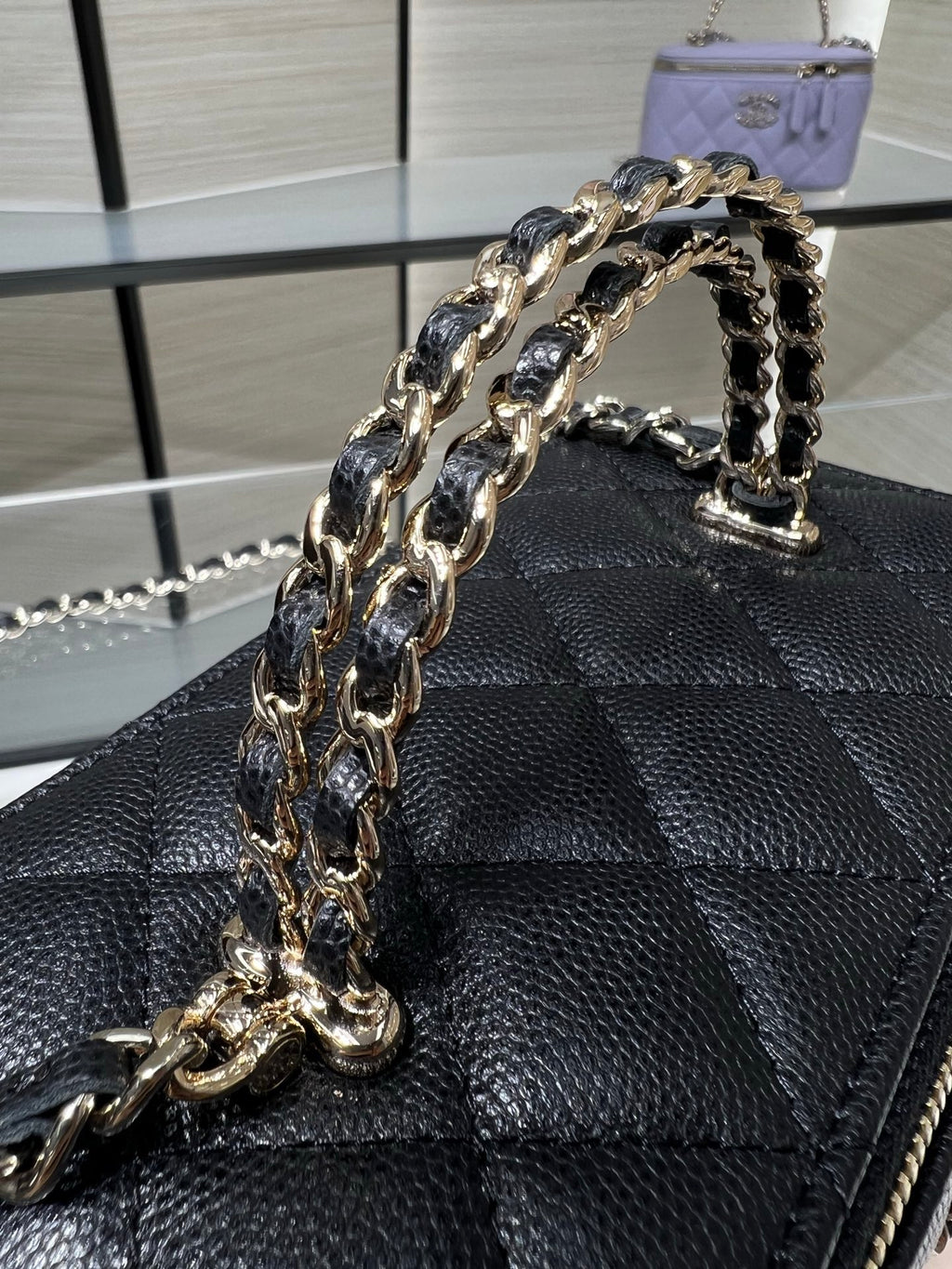 Chanel mini handbag front detail with thick chain strap and quilted leather pattern.
