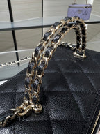 Chanel mini handbag front detail with thick chain strap and quilted leather pattern.
