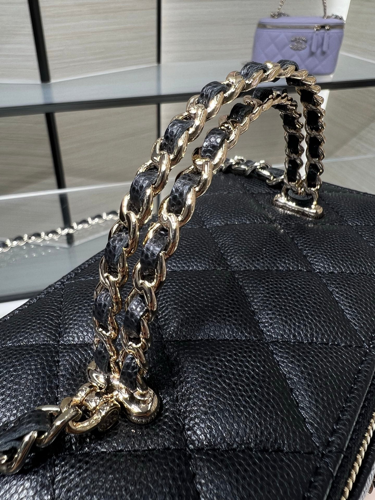 Chanel mini handbag front detail with thick chain strap and quilted leather pattern.