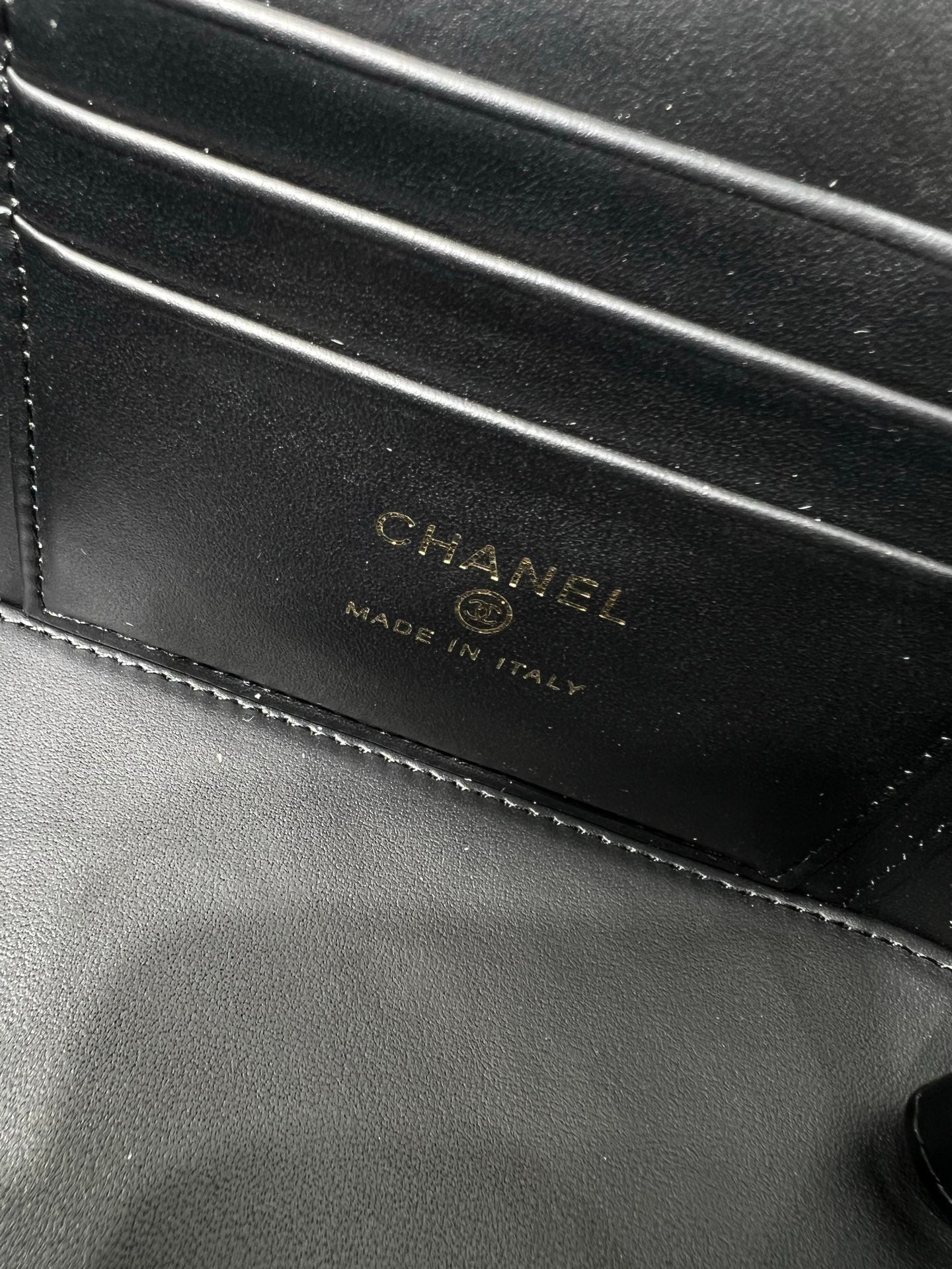 Chanel leather bag close-up with CHANEL branding and 'Made in Italy' stamp.