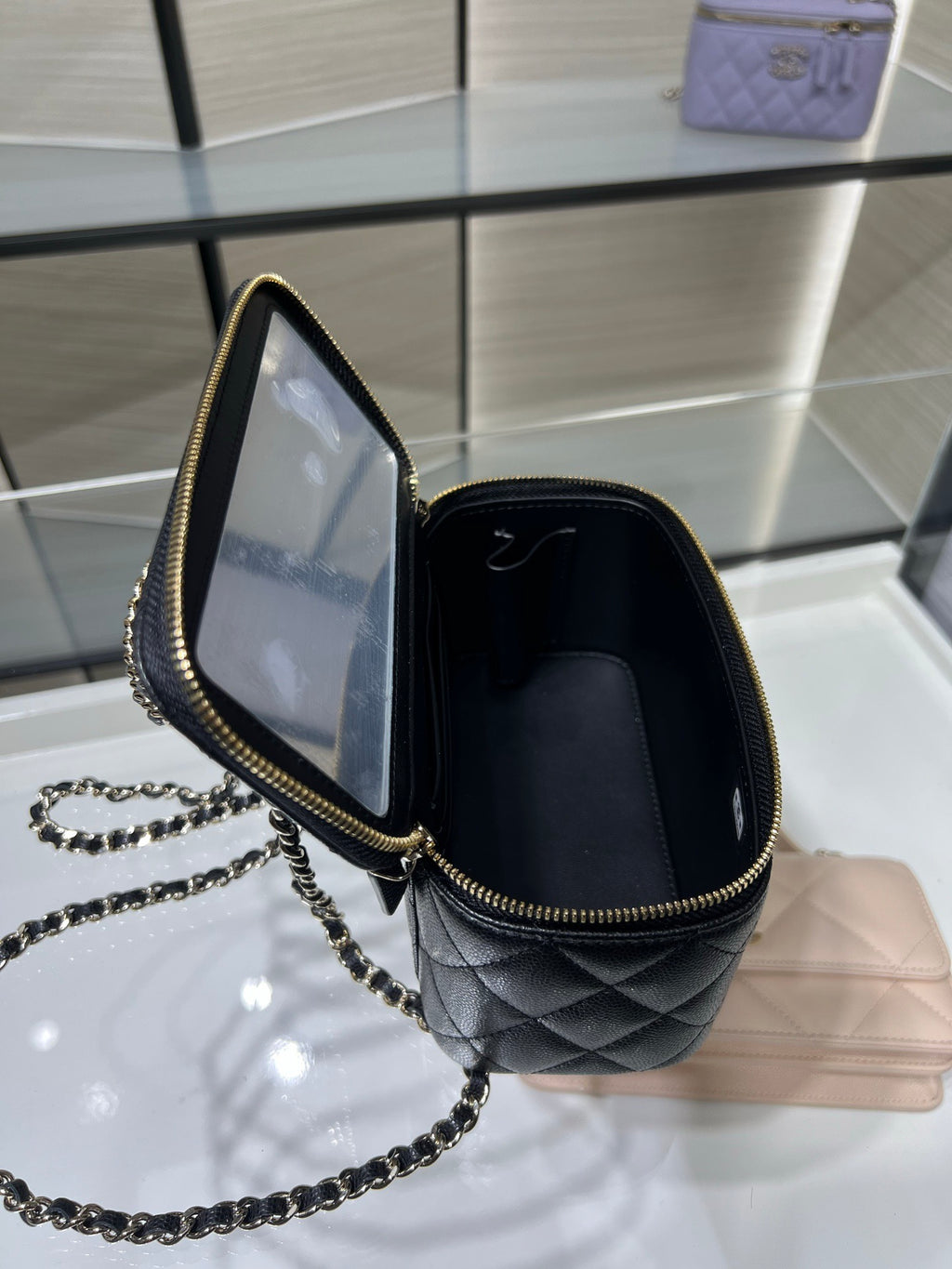 Chanel mini handbag open view with gold zipper, quilted interior and chain strap.