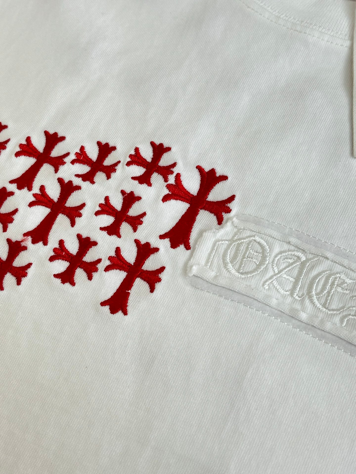 White T-shirt close-up with red logo graphic and embossed logo tab