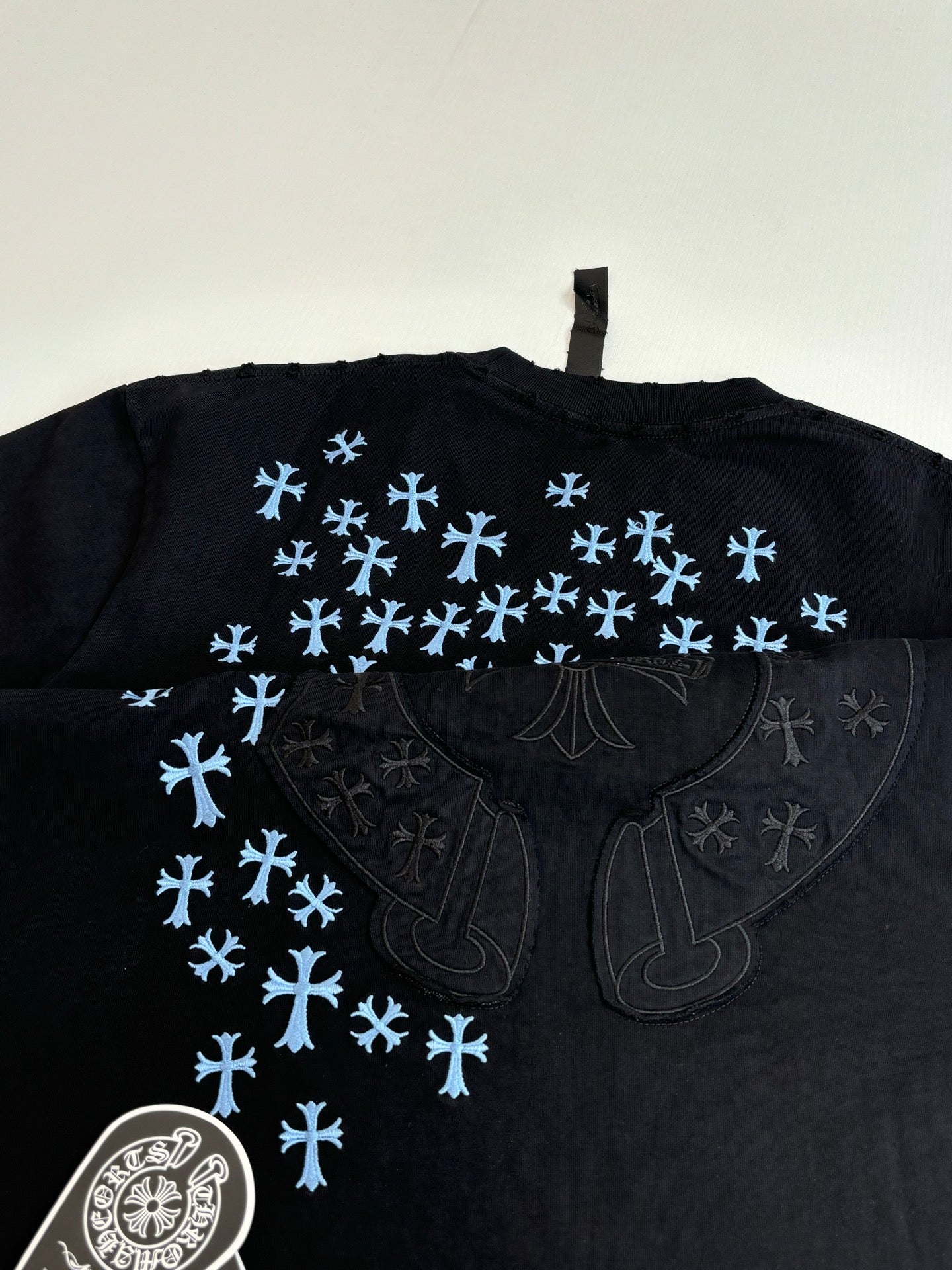 Back of black short-sleeve T-shirt with blue snowflake pattern and large emblem
