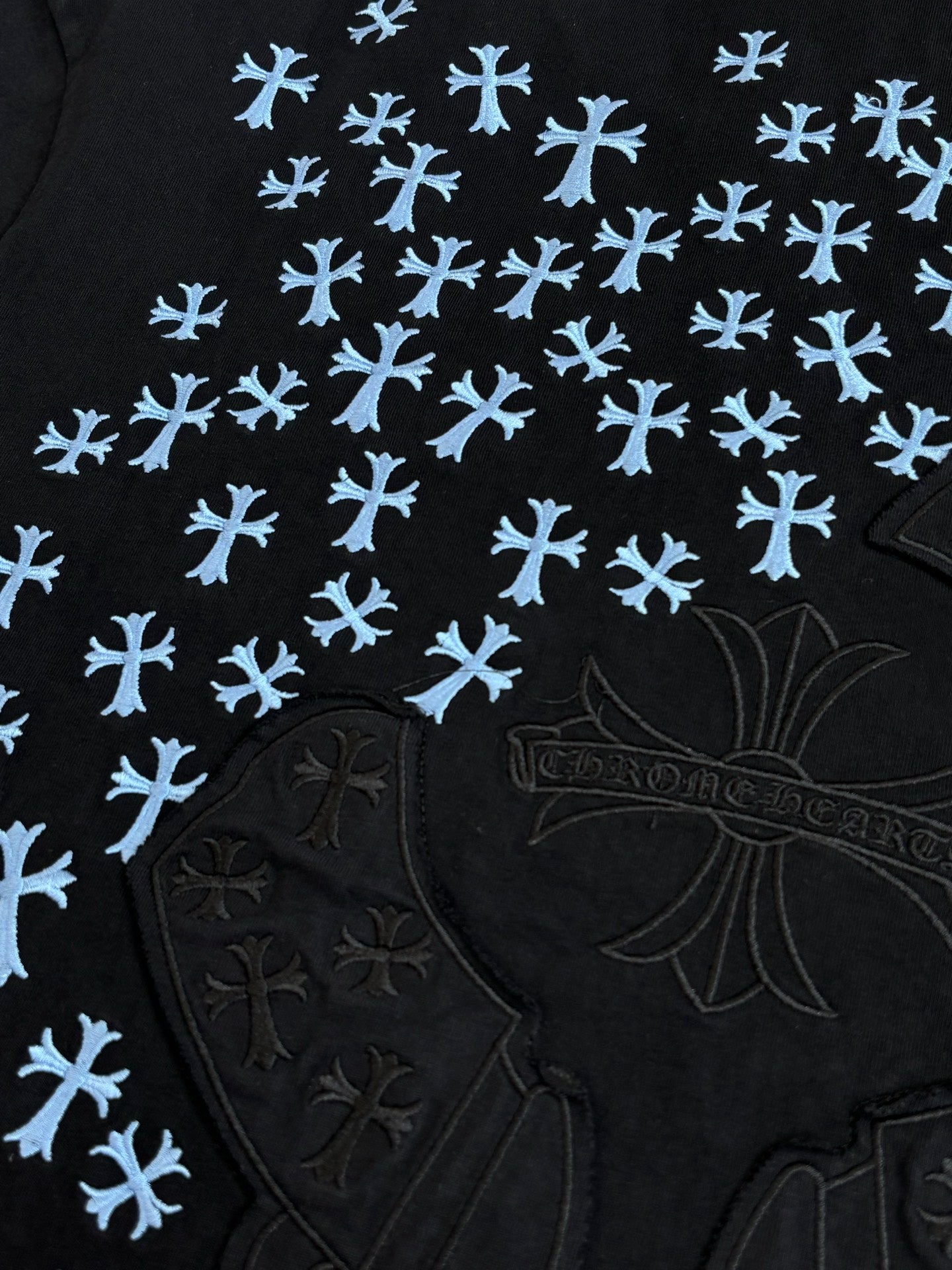 Close-up of black T-shirt with blue snowflake pattern and raised emblem