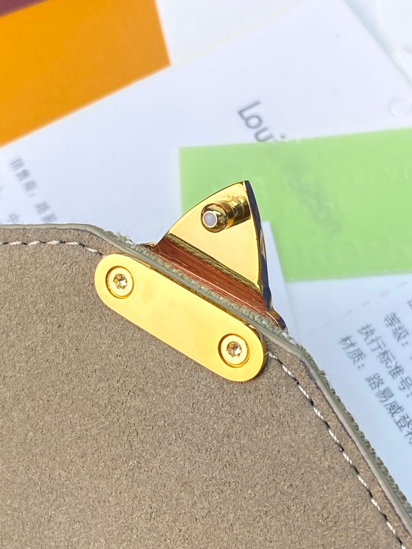 Louis Vuitton bag side strap tab with gold grommets on gray leather
