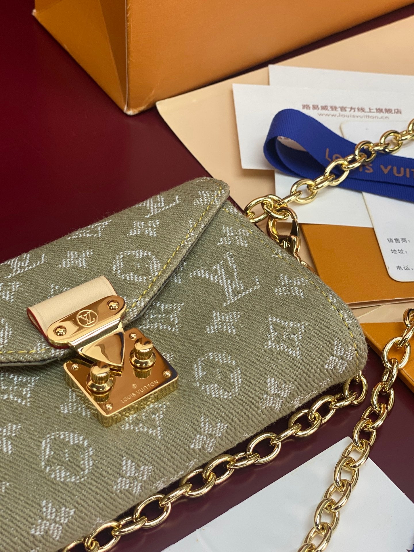 Gray-green monogram mini handbag, close view of gold flap hardware and chain strap